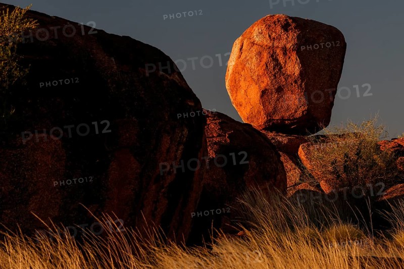 Balancing boulder in the desert, dramatically illuminated by the evening sun, Devil's Marbles, Northern Territory, Australia