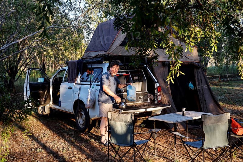 Forest campsite with a car tent and camping equipment in the evening light, Burdulba, Kakadu National Park, Australian Northern Territory