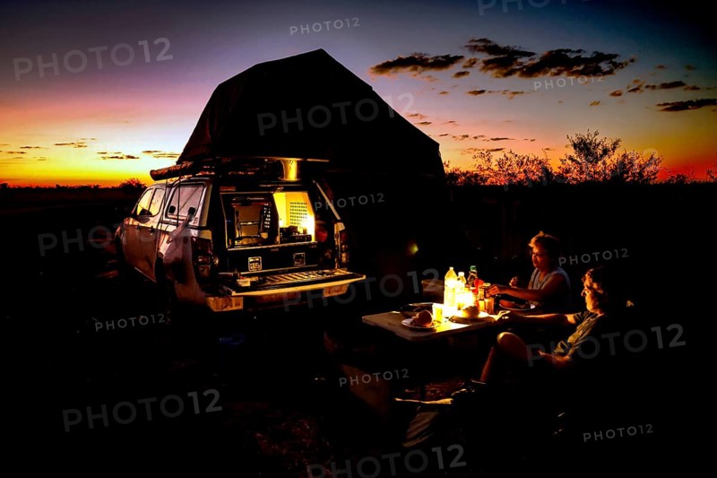 Camping in a van at sunset with bonfire in the Australian desert