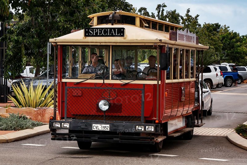 Red tourist bus on Carnarvon Street surrounded by trees, Broome, Western Australia, Australia