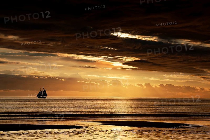 Spectacular sunset with sailboat on horizon over Cable Beach, Broome, Western Australia, Australia