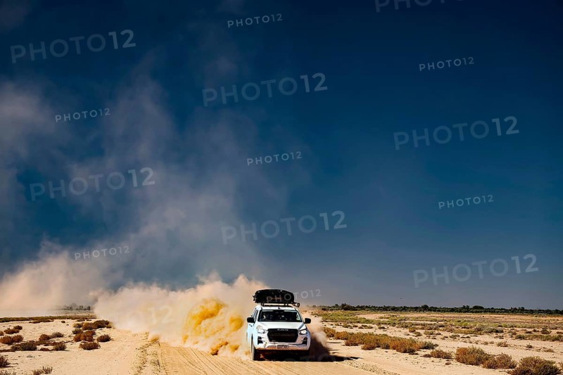 Four-wheel drive vehicle whirls up dust on desert road
