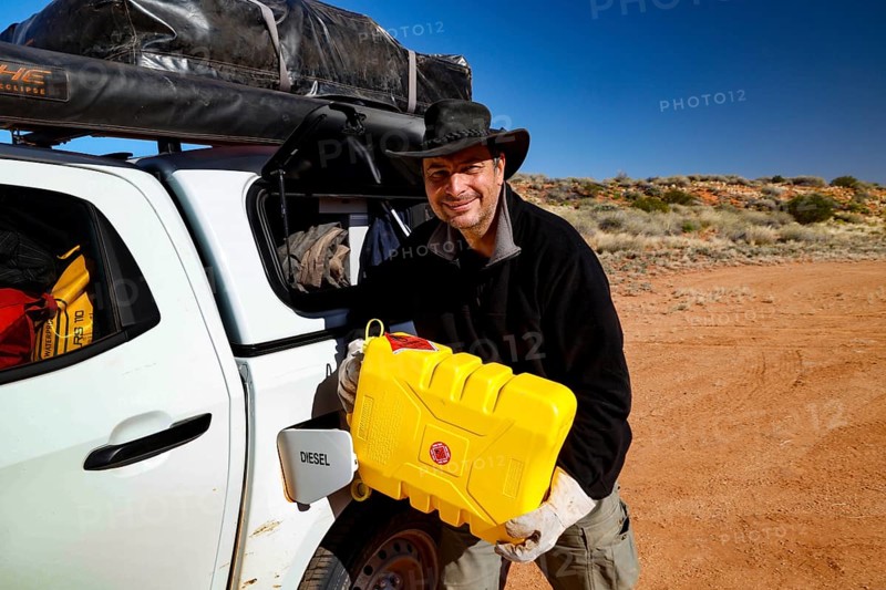 Person refuels vehicle with canister in the desert-like Simpson Desert, Simpson Desert, Australia
