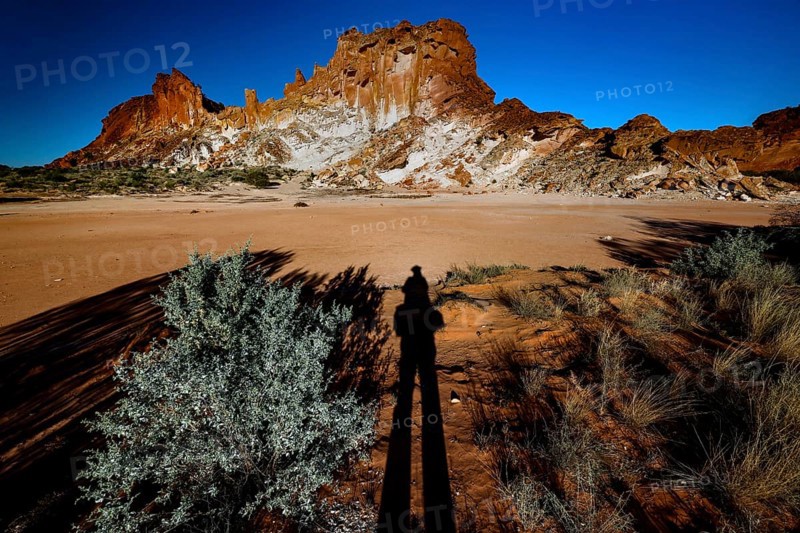 Shade stretches across the desert landscape of Rainbow Valley with distinctive rock formation, zero