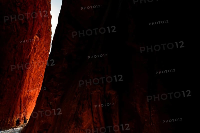 Sunlight falls on the red rocks of Standley Chasm in a dramatic scene, Standley Chasm, Northern Territory, Australia