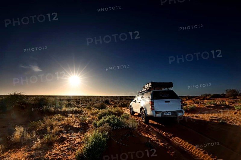 Off-road vehicle on sandy track in Simpson Desert, illuminated by sunrise, Simpson Desert, Northern Territory, Australia