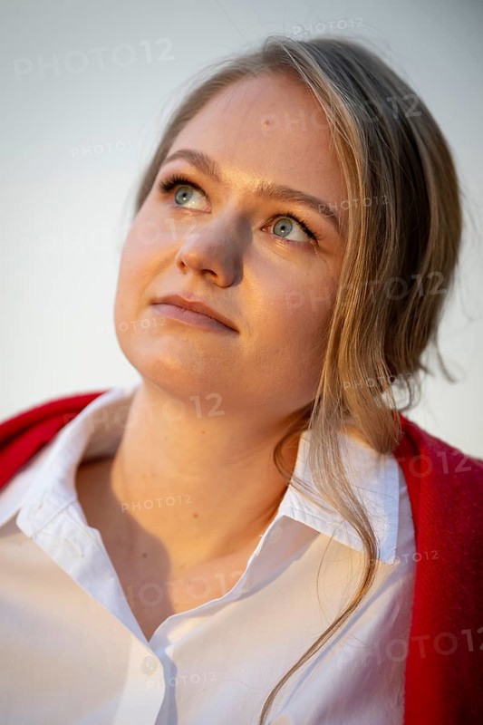 Portrait of a thought-looking young woman, pianist, wearing white blouse and red cardigan, in the evening light, Stuttgart, Baden-Württemberg, Germany