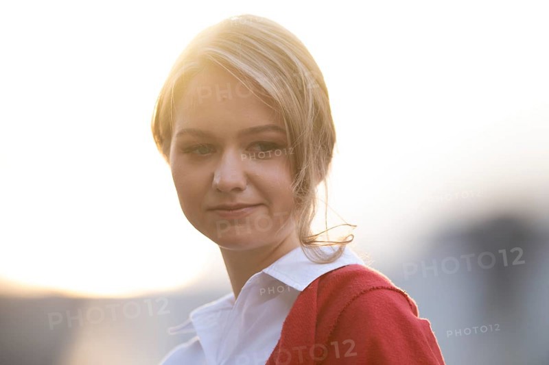 Serious looking young woman in white blouse and red cardigan, in backlight, Stuttgart, Baden-Württemberg, Germany