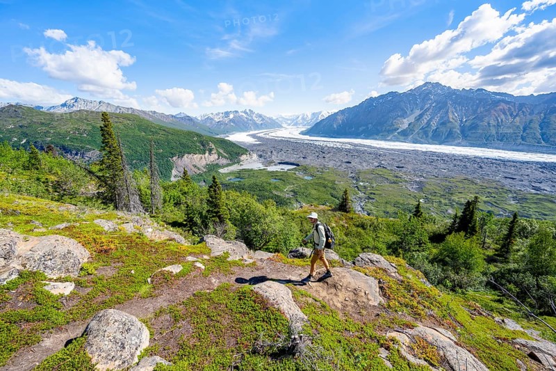 Young man on a hiking trail, view of impressive mountain landscape with Matanuska glacier and glaciated mountain peaks, Lion's Head, Chugach Mountains, Alaska, USA