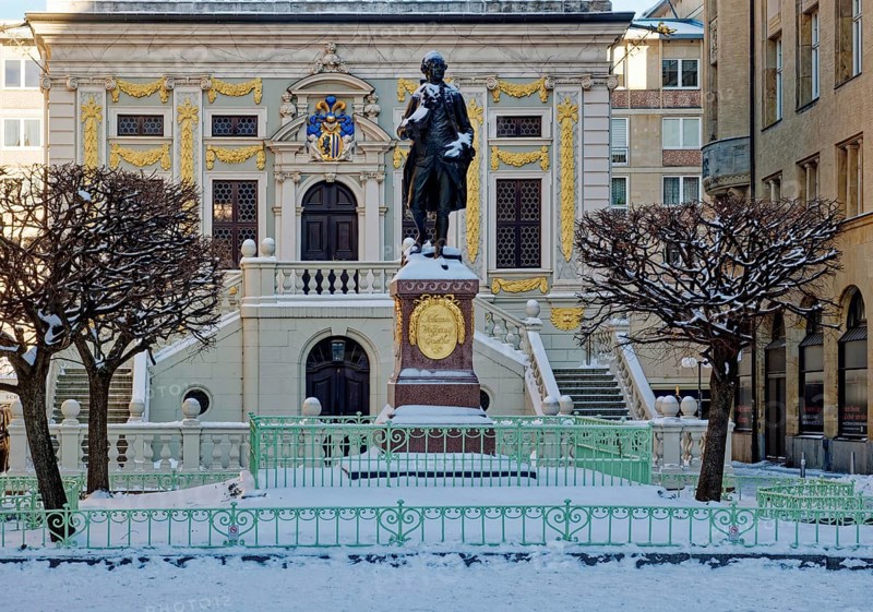 Baroque Old Trade Exchange, bronze statue of the Goethe monument by Carl Seffner depicting Johann Wolfgang von Goethe, at Naschmarkt in winter with snow, Leipzig, Saxony, Germany
