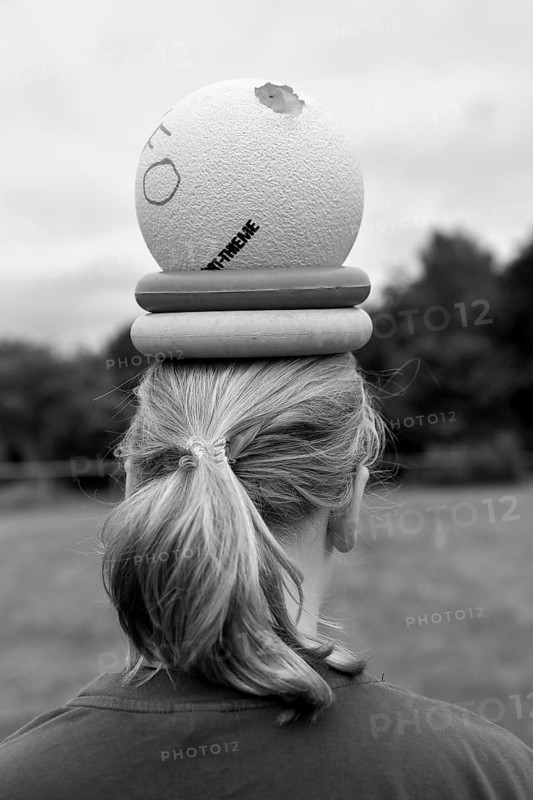 Person with ball and wrestling on head, environment in nature, sports and fun Olympics sports festival school, Lower Saxony, Germany