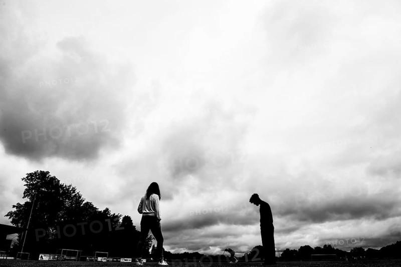 Two silhouettes of people under dramatically cloudy sky on a sports field, sports and fun Olympics Sportfest Schule, Lower Saxony, Germany