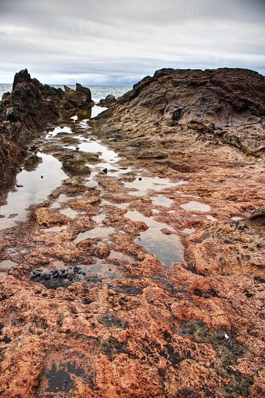 Close-up of rocky coastline with puddles, dramatic sky in background, Chargo Verde El Golfo Lanzarote