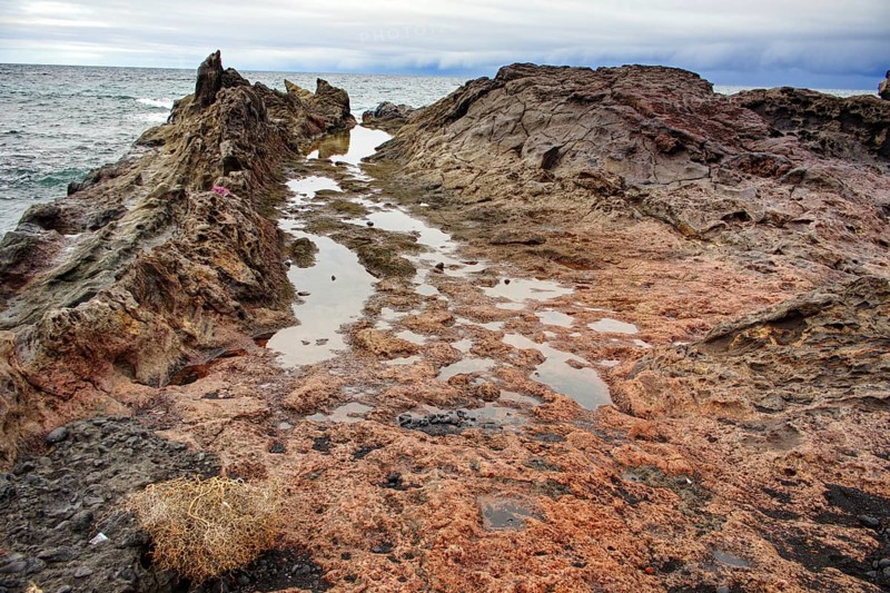 Rough coastline with rugged rocks and small waves under a cloudy sky, Chargo Verde El Golfo Lanzarote