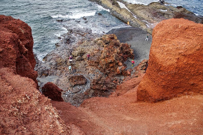 Red rock cliffs with people looking out at the wavy coast and the vast sea, Chargo Verde El Golfo Lanzarote