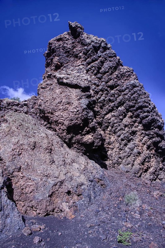 View of a high volcanic rock structure under a clear blue sky, partial view of El Cuervo volcano, Tinajo Lanzarote