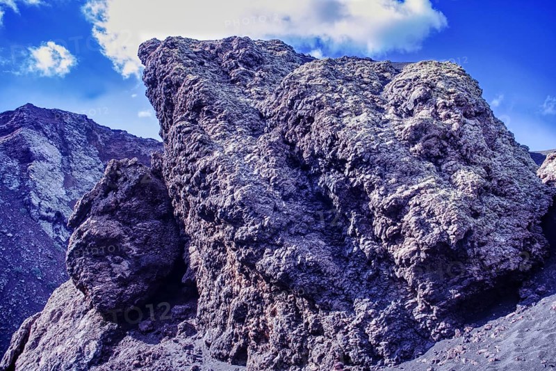 Impressive rock formation of volcanic rock rising against a blue sky, partial view of El Cuervo volcano, Tinajo Lanzarote