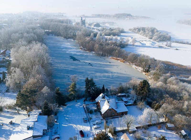 Snowy landscape with a frozen lake surrounded by trees and houses in fog, aerial view, Oelsburg, Ilsede, Peine district, Lower Saxony, Germany