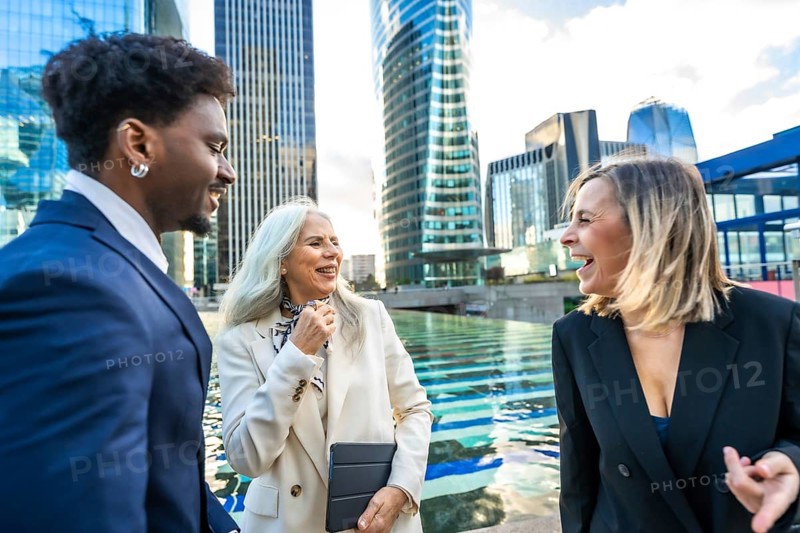 Diverse business professionals having a joyful outdoor conversation and networking session in a modern urban environment, fostering teamwork and positive interactions