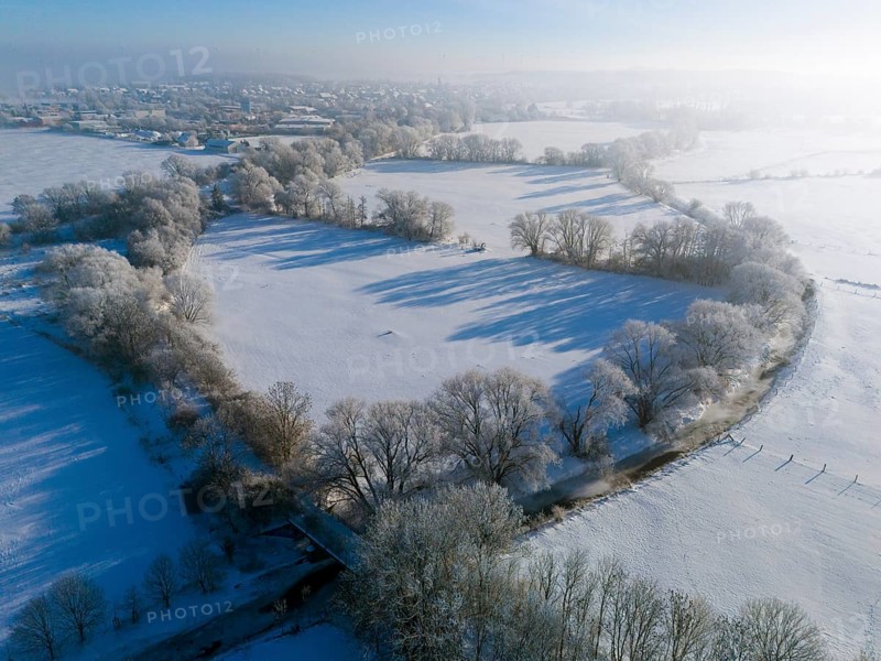 Winter landscape with snowy fields and trees, city skyline in the background under blue sky, Fuhse river, Bülten, Ilsede, Peine district, Lower Saxony, Germany