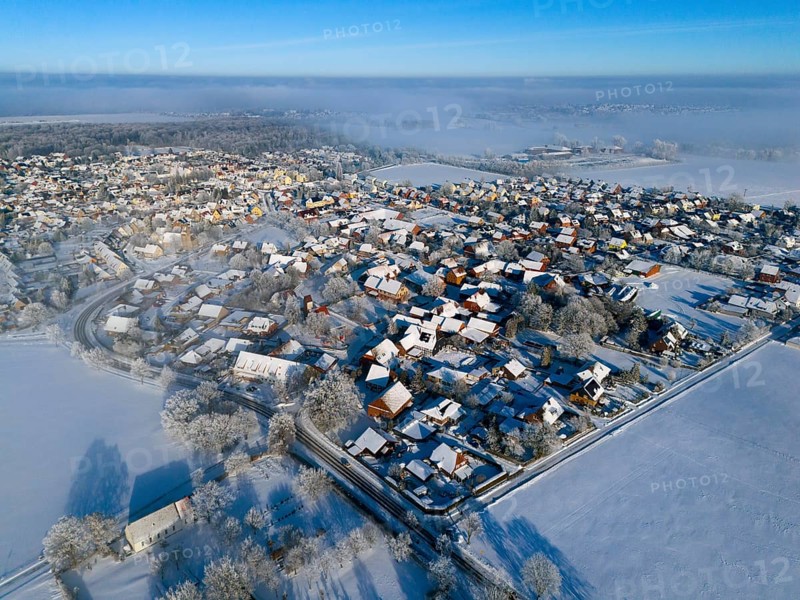 Snowy village under clear sky, sunlight reflected on white roofs and trees, aerial view, partly fog, Bülten, Ilsede, Lower Saxony, Germany
