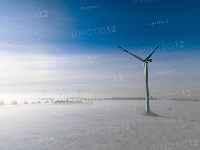 Wind turbine rises above foggy snow-covered landscape in clear blue sky, aerial view, wind turbine in snow in fog, between Bülten and Solschen, Ilsede, Peine district, Lower Saxony, Germany