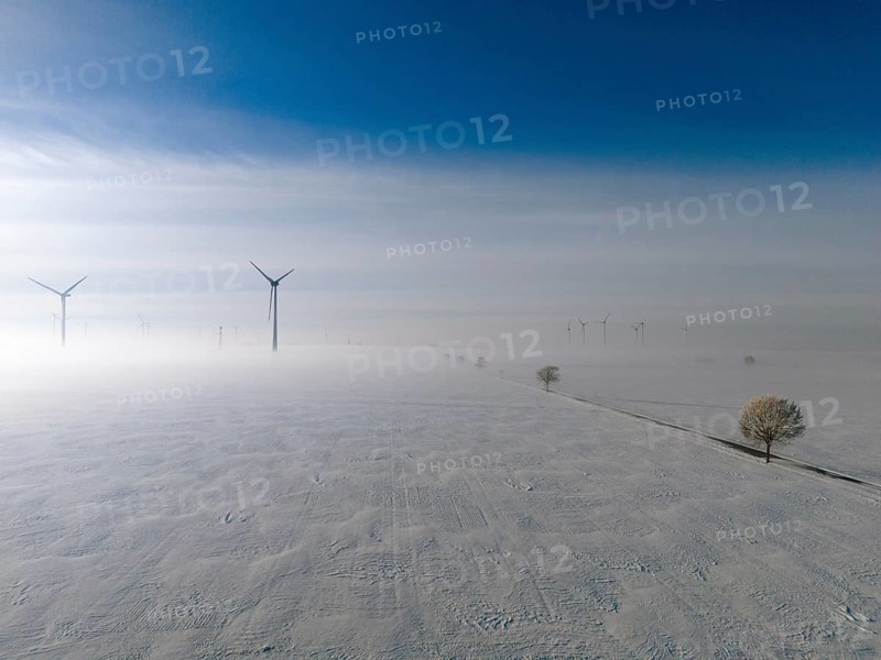 Wide snow-covered plain with wind turbines in fog under blue sky, aerial view, wind turbine and tree in snow in fog, between Bülten and Solschen, Ilsede, Peine district, Lower Saxony, Germany