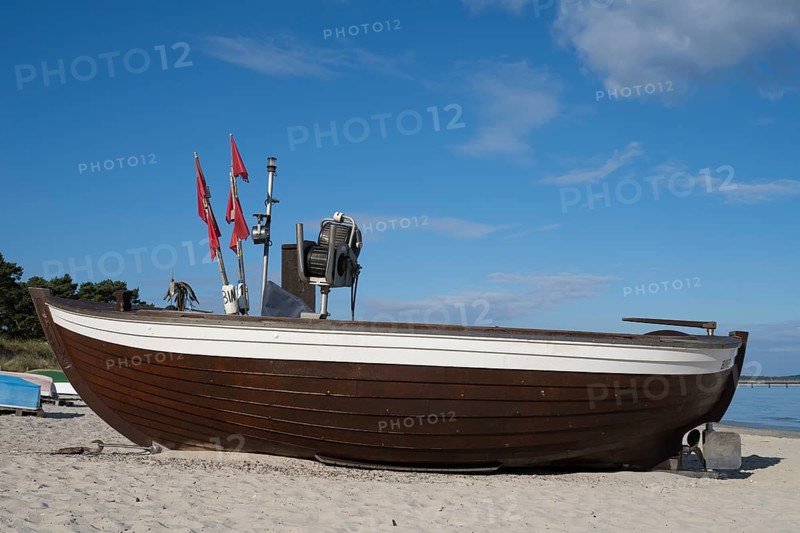 Boat with fishing flags lying on sandy beach, blue sky, Binz, seaside resort, Rügen island, Baltic Sea, Mecklenburg-Western Pomerania, Germany