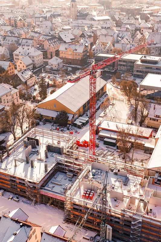 Snowy town with a construction site and a distinctive red crane, Zellerschule building, Nagold, Black Forest, Germany