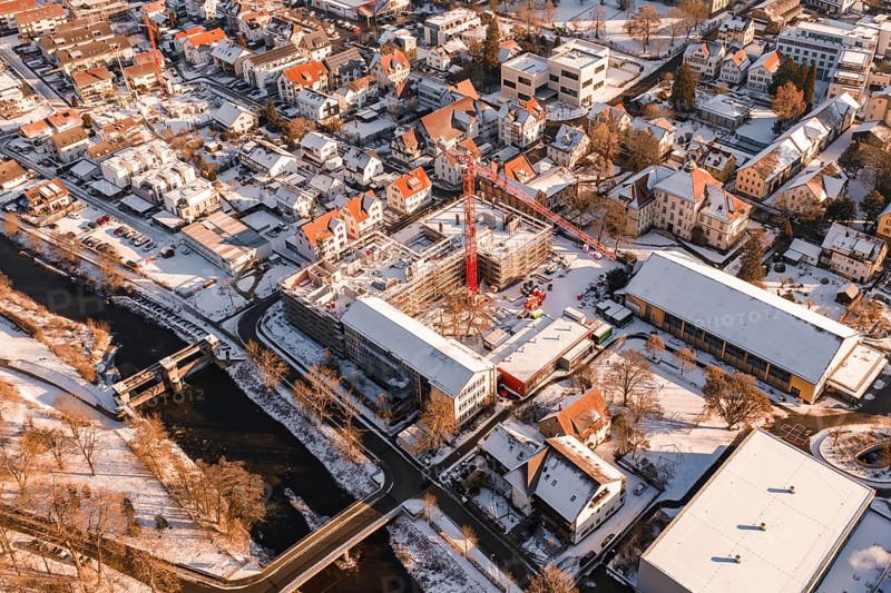 Snowy town with a red construction crane on a construction site and a river, Neubau Zellerschule, Nagold, Black Forest, Germany