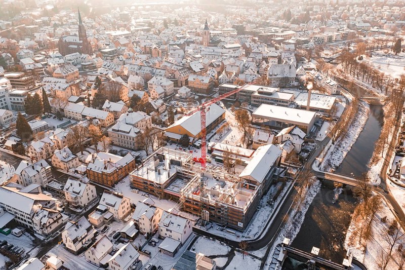 City in winter with an active construction site and visible church roof in the background, Zellerschule building, Nagold, Black Forest, Germany