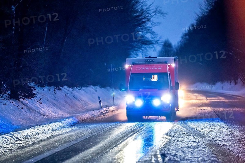 Ambulance during an alarm trip, with flashing lights, in winter, slush, slippery roads, country road near Marienheide, Bergisches Land North Rhine-Westphalia, Germany