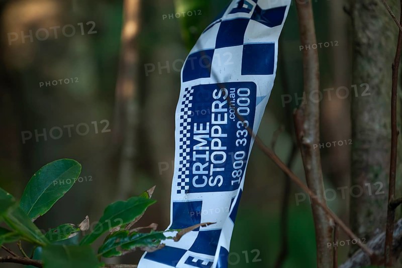 Crime scene, Byron Bay, New South Wales, Australia. Police tape blocks a forest path during an investigation in the bush