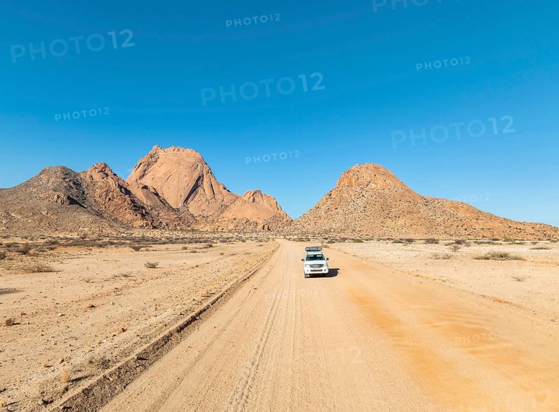 Car on sandy road, mountains in the desert, Spitzkoppe summit, Namib desert, Namibia