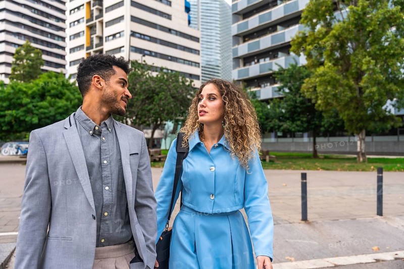 Business colleagues having a discussion while walking through a contemporary urban area, presenting teamwork, networking, and professional interaction in a modern city setting