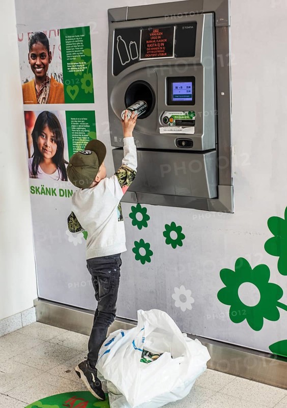 Boy, 7 years old, earns pocket money by recycling cans in recycling machine in Ystad, Skåne County, Sweden, Scandinavia