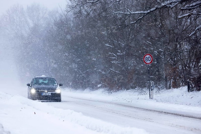 Road traffic in winter, car driving on heavily icy road covered with snow and black ice in a snowstorm, risk of accident, Schleswig-Holstein, Germany