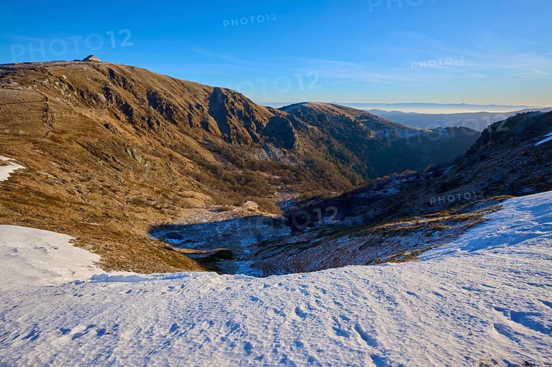 Deep snowy valley in the mountains with clear blue sky in the distance, winter, Route de Cretes, Hohneck, La Bresse, Vosges, France