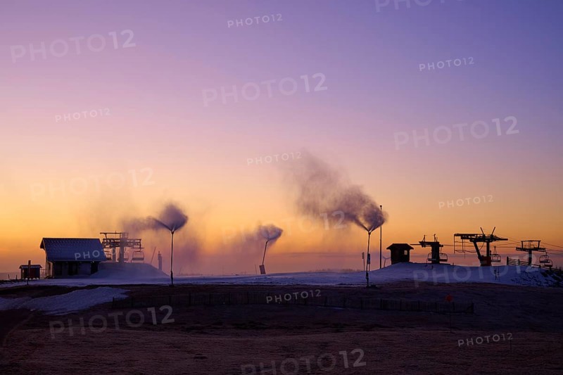 Snow cannons blow smoke under purple and orange evening sky, winter, Route de Cretes, Hohneck, La Bresse, Vosges, France