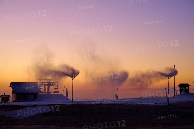 Under a dramatic sunset sky, snow cannons blow smoke across the empty hill, Winter, Route de Cretes, Hohneck, La Bresse, Vosges, France