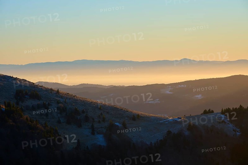 Mountain landscape at sunset with golden sky and hills, European beech, winter, Hohneck, La Bresse, Vosges, France