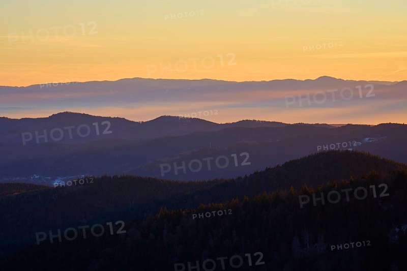Mountains in silhouette at sunrise in warm shades of orange and yellow, view, Rhine Valley, Hohneck, La Bresse, Vosges, France