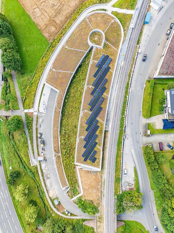 Aerial view of a building with solar panel, surrounded by roads and green vegetation, new park and ride parking garage Calw Heumaden on the new Hermann Hessebahn, Calw, Germany