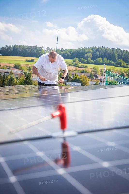 Worker checking solar modules in a landscaped area with clear skies, new park and ride Calw Heumaden car park on the new Hermann Hessebahn, Calw, Germany