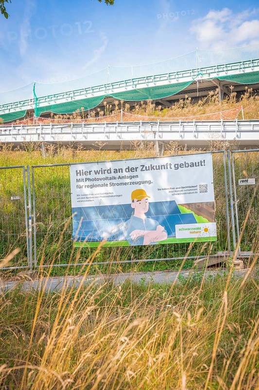 Construction site with advertising for photovoltaic systems for regional power generation under blue skies, new Park and Ride Calw Heumaden car park on the new Hermann Hessebahn, Calw, Germany