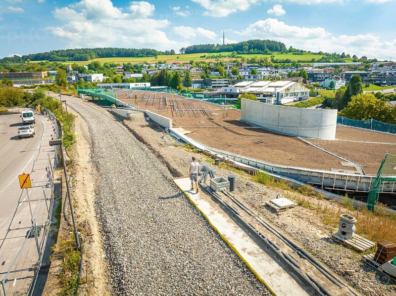 Large construction site for solar systems next to a village with green hills in the background, new Park and Ride Calw Heumaden car park on the new Hermann Hessebahn, Calw, Germany