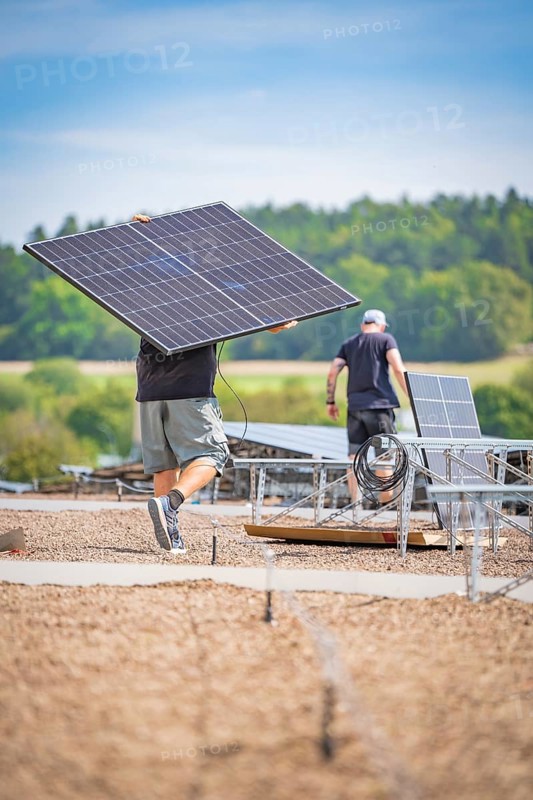Workers install solar panels with cables in an open field under a blue sky, new park and ride parking garage Calw Heumaden on the new Hermann Hessebahn, Calw, Germany