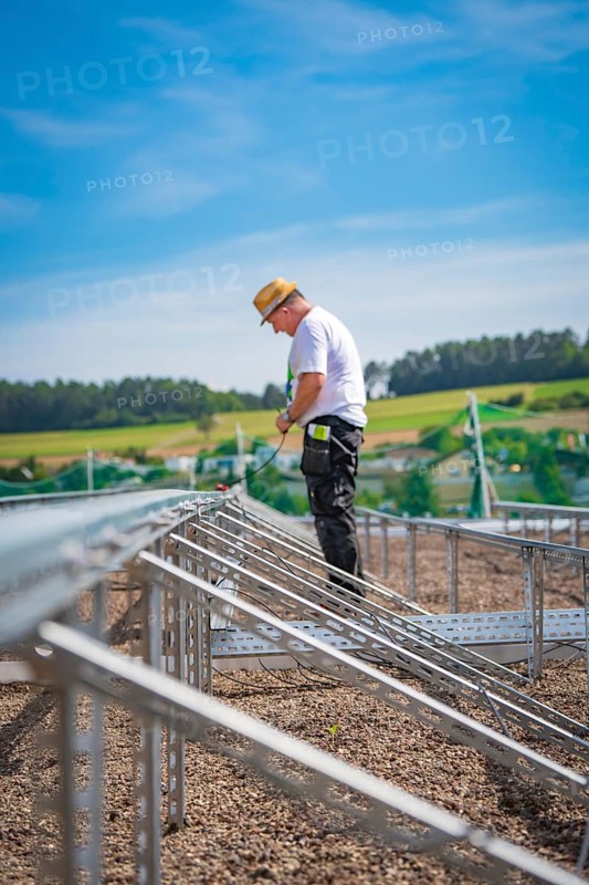 A construction worker stands on scaffolding in a rural area under blue skies, new park and ride parking garage Calw Heumaden on the new Hermann Hessebahn, Calw, Germany