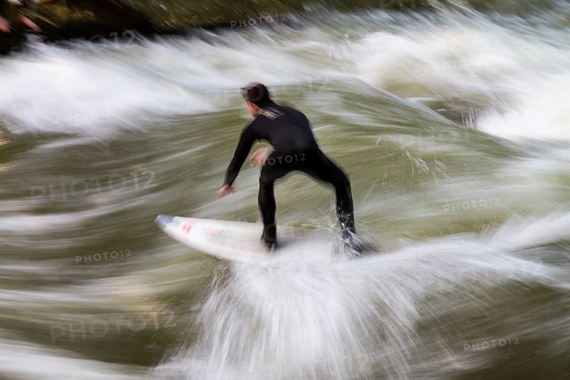 Surfers standing on Eisbach wave in the English Garden Munich, Upper Bavaria, Germany