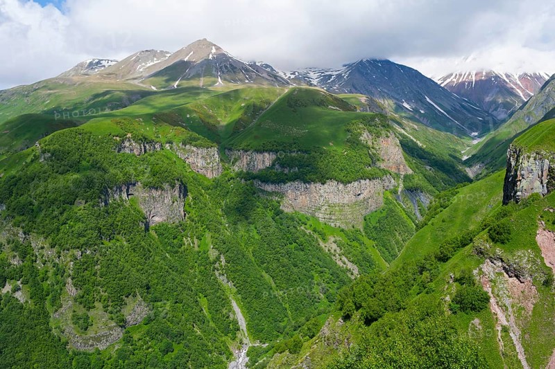 Green mountains with deep gorges under cloudy sky, mountainous landscape between Gudauri and Cross Pass, Mount Sherkhota, Mtskheta-Mtianeti region, Georgian Military Highway, High Caucasus, Georgia